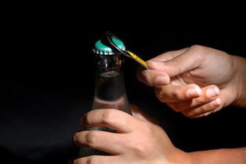 Female hand opening bottle using metal opener with isolated black background