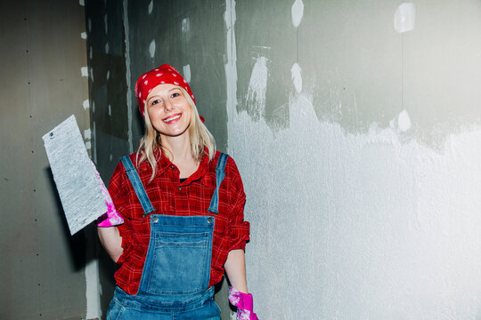 Confident woman plastering drywall during home renovation project