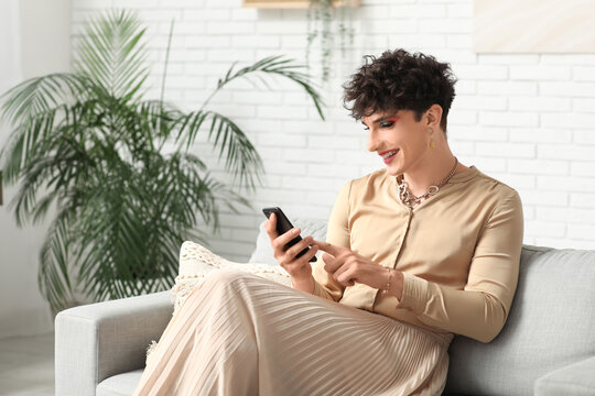 Young transgender woman using mobile phone on sofa at home - Powered by Adobe