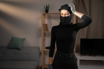 Portrait of confused expression female thief in black balaclava who mistake and thinks how to solve...