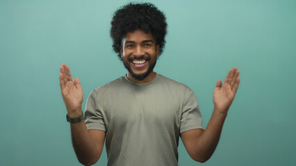 Man gesturing large size with hands against green background, smiling and wearing casual outfit,...