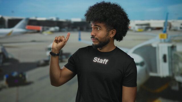 Man pointing with finger at airport in staff uniform outdoors highlighting aviation environment for african american context and travel assistance.