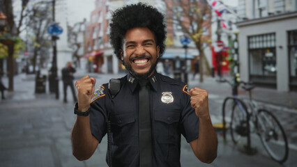 African american man in police uniform celebrating with fists raised on a city street surrounded by...