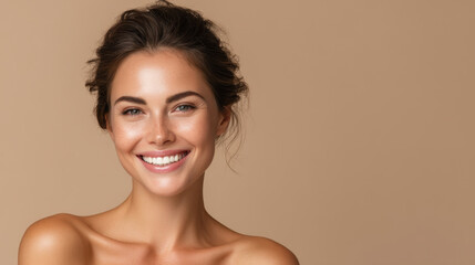 Obraz premium Smiling woman with clear skin and natural makeup poses against neutral background, exuding confidence and warmth. Her hair is styled in loose waves, enhancing her radiant appearance