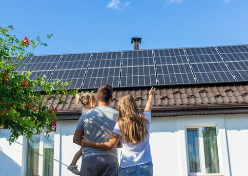 happy family on the background of a house with solar panels on the roof. Selective focus