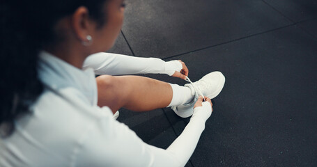 Sneakers, fitness and woman tying laces in gym for workout, safety or training for wellness. Shoes, athlete and top view of person getting ready for exercise, health or cardio in sports center.