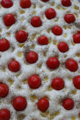 Not baked italian traditional Focaccia with red cherry tomatoes and thyme herb background