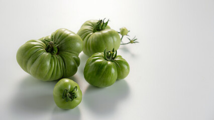 Unique varieties of green tomatoes arranged artistically on a clean white background