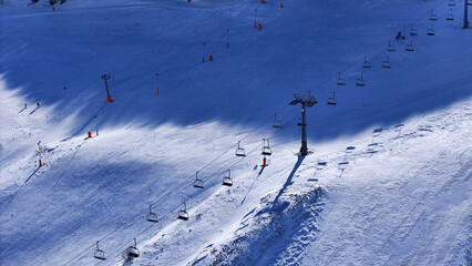 Snowy landscape showcases ski lifts stretching across a mountain under a brilliant blue sky, capturing the essence of winter recreation