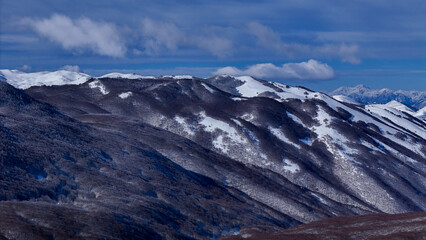 Snow-capped mountains rise majestically under a bright blue sky in a serene winter landscape