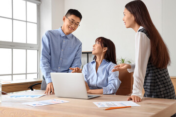 Obraz premium Chinese business people working with laptop at table in office