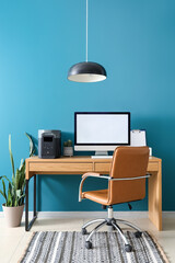 Portable power station with blank computer monitor on table near blue wall in office