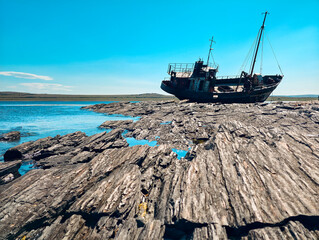 old wrecked sunken ship on the rocky shore of the Arctic Ocean is the