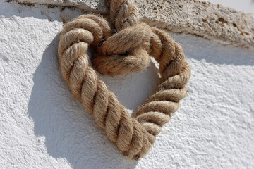 beautifully arranged rope forming heart shape is artistically displayed against clean bright white wall