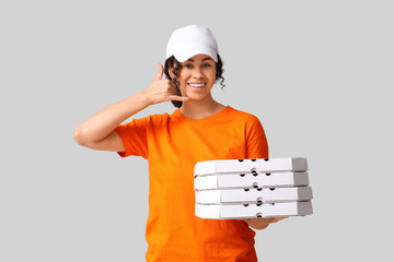 Female African-American courier holding cardboard boxes with tasty pizza and showing CALL ME...