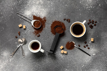 Scoops with coffee powder and cup of coffee on grey grunge background