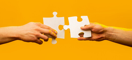 Hands connecting puzzle pieces. Male and female hand joining two matching puzzle pieces together in a conceptual image of teamwork and cooperation
