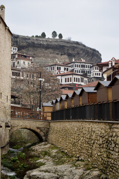 View of traditional Ottoman houses with white walls and red roofs cascading down the hillside above a stone bridge and stream, Safranbolu, Karab&Atilde;&frac14;k, T&Atilde;&frac14;rkiye.