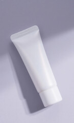 Blank white cosmetic tube mockup for cream or skincare product. Minimalist beauty packaging on a pastel purple background with soft shadow.