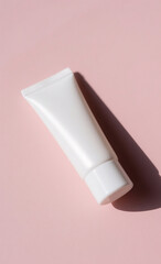 Cosmetic cream tube with a white cap casting a shadow on a pink surface