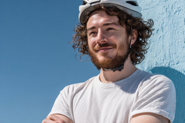 man wearing bicycle helmet stands confidently on ultrabright light blue background