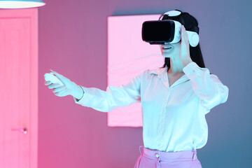 Young woman with VR glasses and controller in modern art gallery