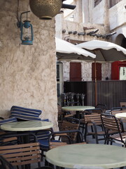 A Seder Ted outdoor cafe with stacked chairs, tables, and an antique lantern against a stone wall. 