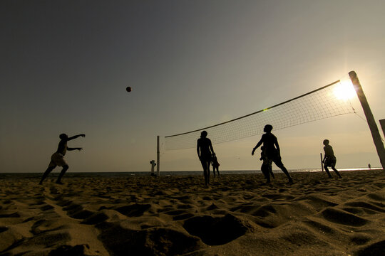 View of silhouettes playing volleyball on the sandy beach under the bright sun near the water, creating a striking contrast, Bujumbura, Bujumbura Mairie, Burundi.
