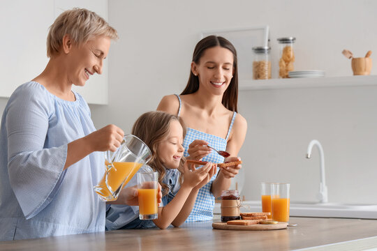 Happy family drinking juice with toasts in kitchen