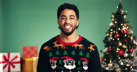 Studio, man and excited for Christmas, portrait or festive celebration with decorations or presents. Happy, person and green background for Xmas season, December and tree with ornaments on holiday