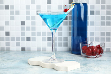 Glass of tasty Blue Lagoon cocktail garnished with cherry on light table