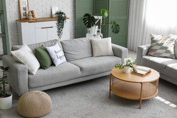 Interior of light living room with grey sofas, table and green plants