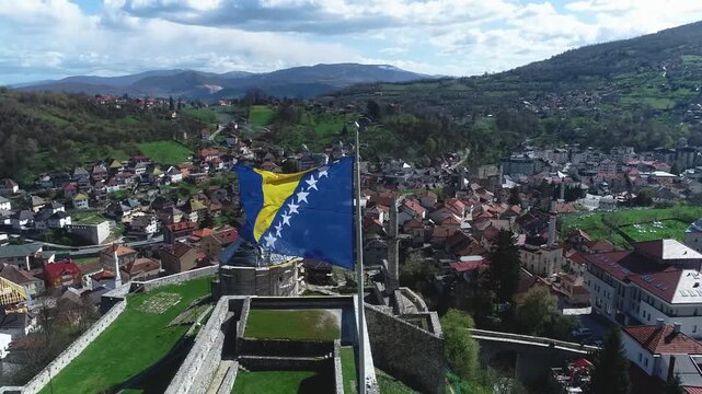 Flag of Bosnia and Herzegovina waving on the historic Travnik fortress, symbol of national pride and cultural heritage.