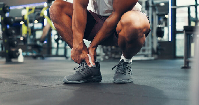 Ankle injury, fitness and hands of person in gym for physical training or workout accident. Exercise, legs and pain with hurt athlete in health club for emergency, joint inflammation or sprain