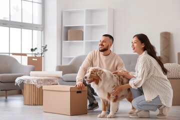 Young couple with box and Australian Shepherd dog in room on moving day