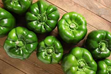 Many green bell peppers on wooden background