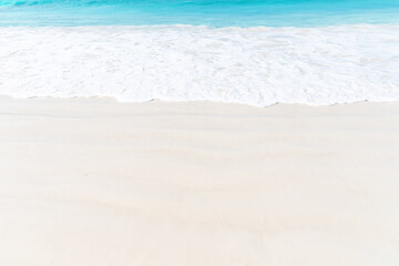 The idyllic scene of turquoise ocean waves gently rolling onto a pristine white sand beach