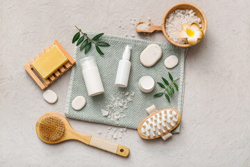 Spa composition with towel, stones, jar and bottles of cosmetic products on white grunge background, closeup