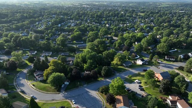 Aerial establishing shot of quiet and peaceful neighborhood in suburb ion america. Sunny day with green trees in summer. Houses and homes with garden on hill.