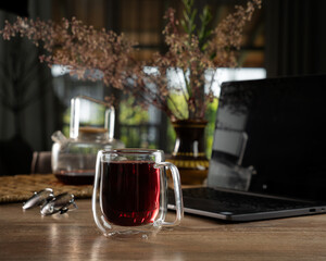 Enjoying a warm beverage at a cozy workspace in the afternoon sunlight with laptop and flowers