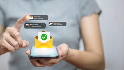 Hand holding smartphone with email notification icons, digital communication and alert concept