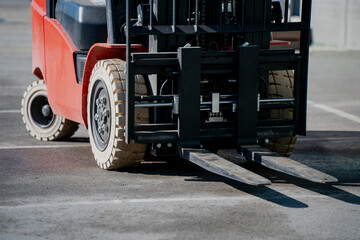 Red forklift truck with metal forks closeup on industrial site, heavy duty warehouse equipment for cargo lifting and material handling, logistics machinery detail in outdoor loading area