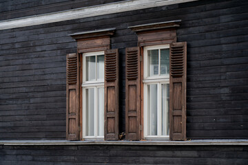 Rustic wooden wall with symmetrical windows and aged shutters, traditional architectural element of historic timber house facade, heritage construction detail with cultural design aesthetics