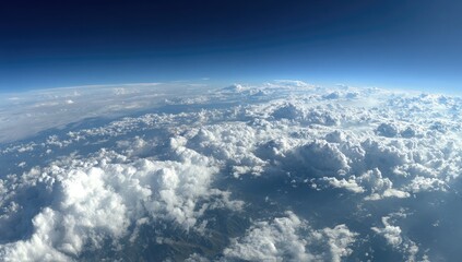 Vast expanse of clouds from high altitude, stretching across the horizon.  A pale blue Earth is visible below, framed by a deep blue sky.  Dense, puffy white clouds cover much of the view