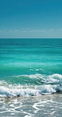 Turquoise ocean waves gently lapping a sandy shore against a vibrant blue sky