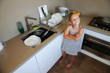 Stressed girl in kitchen with sink full of dirty dishes