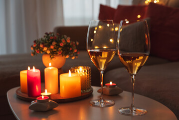Cozy evening scene with candles, wine glasses and warm lighting.