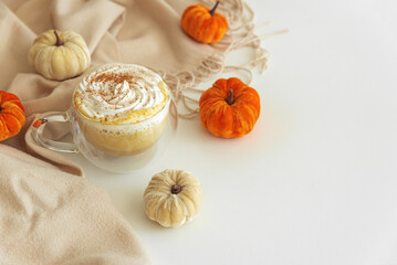 Cozy pumpkin latte with whipped cream and spices, surrounded by autumn decor.