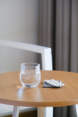 blisters with pills and glass of water on the table