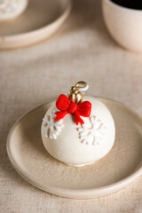 Christmas ball cake with a red bow and snowflakes on the table. Vertical orientation.